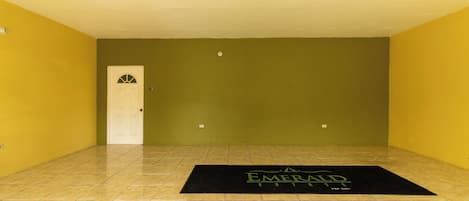 A room with yellow walls, a white door, and a black mat with 'Emerald' text.