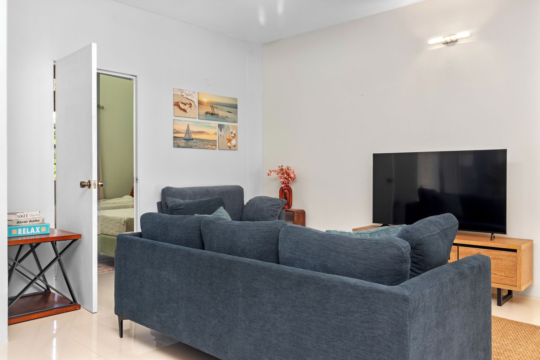 A modern living room with a grey sofa, a flat-screen TV, and a small wooden side table.