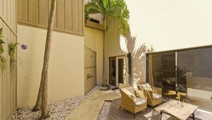 A patio area with wicker furniture, a palm tree, and a small table with a plant.