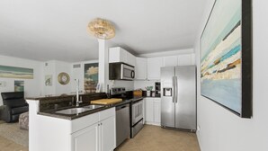 A modern kitchen with white cabinets, stainless steel appliances, and a large island.