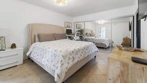A bedroom with a bed, bedside table, mirror, and a wooden dresser.