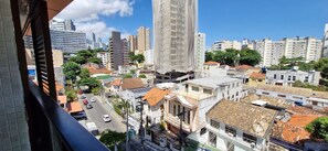 A cityscape with a mix of high-rise buildings and older structures, a clear sky, and a street with cars. - COBAR0143 - Edifício ZN Barra (Salvador)