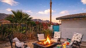 Eine Terrasse mit Feuerstelle, Gartenmöbeln und Blick auf Berge.