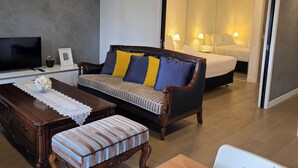 A modern living room with a sofa, a wooden coffee table, a TV, and a dining area. - Apartment in Windsor (MELBOURNE)
