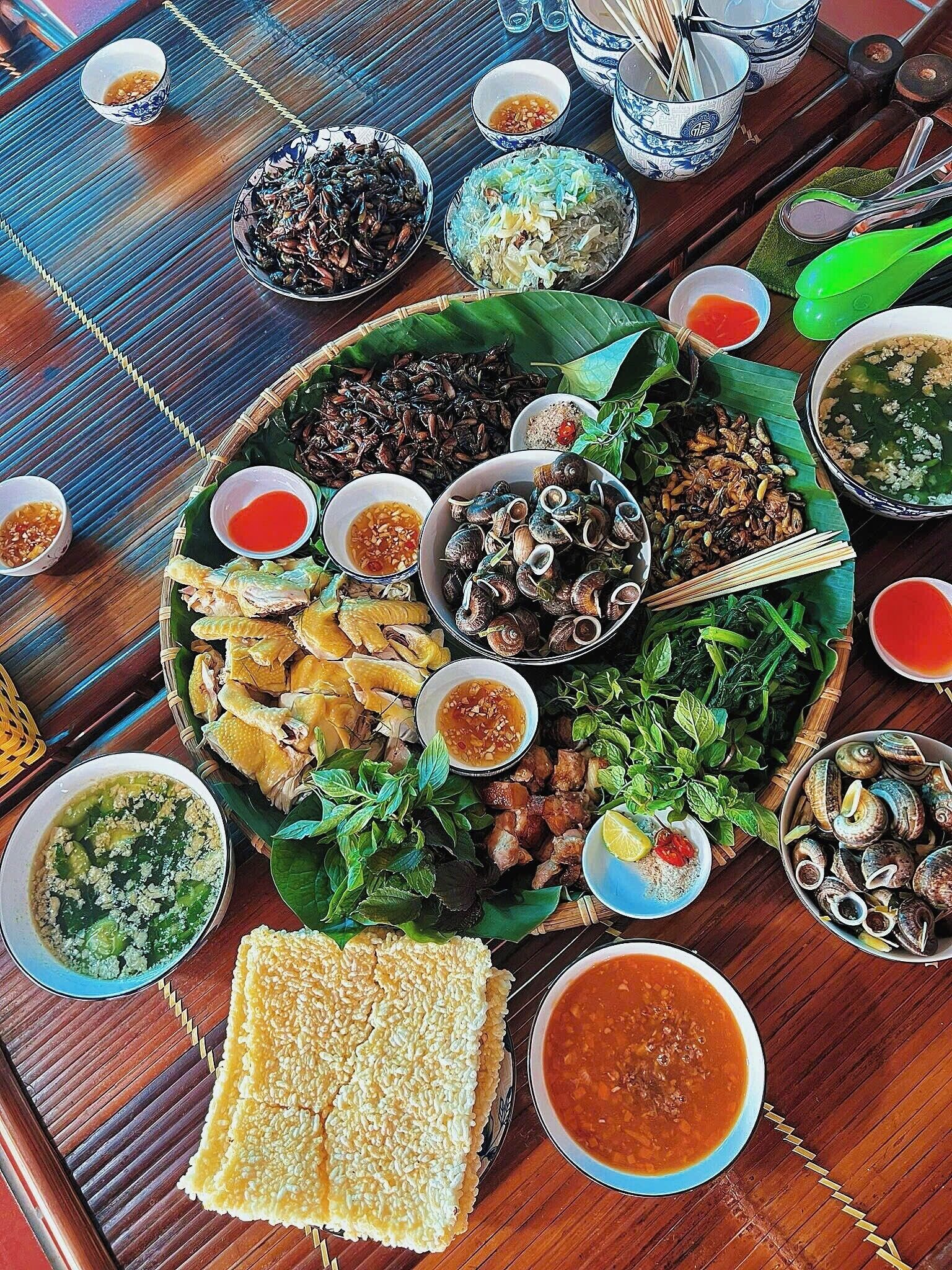 A variety of dishes and condiments arranged on a wooden table, suggesting a meal setting.