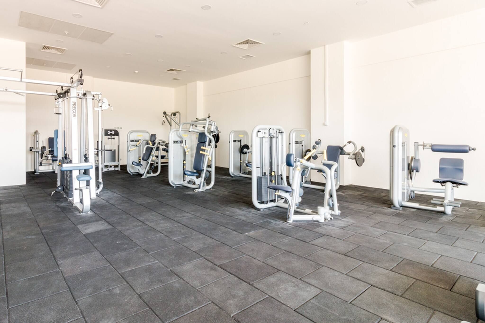 Een sportschool met diverse fitnessapparaten in rijen opgesteld.