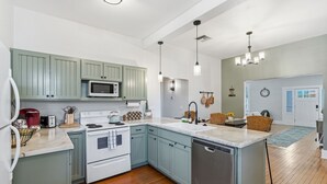 Une cuisine moderne avec des meubles de couleur bleu clair, des appareils en acier inoxydable et un îlot central.