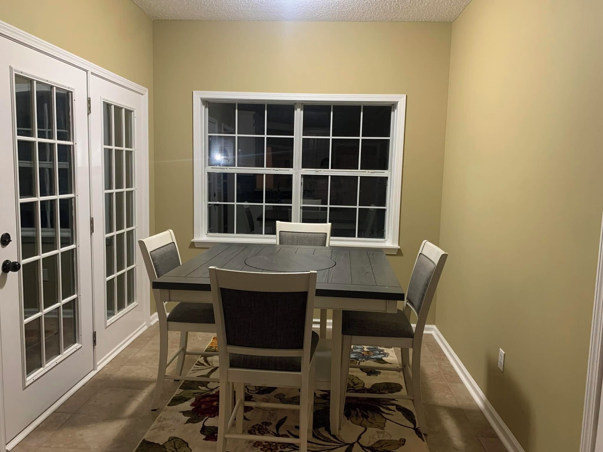 A dining area with a table and chairs, a window, and a door with glass panels.