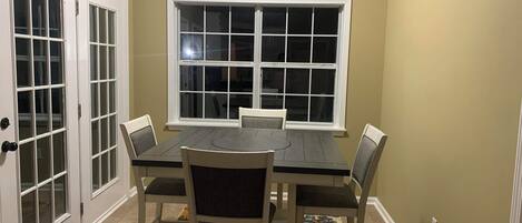 A dining area with a table and chairs, a window, and a door with glass panels.