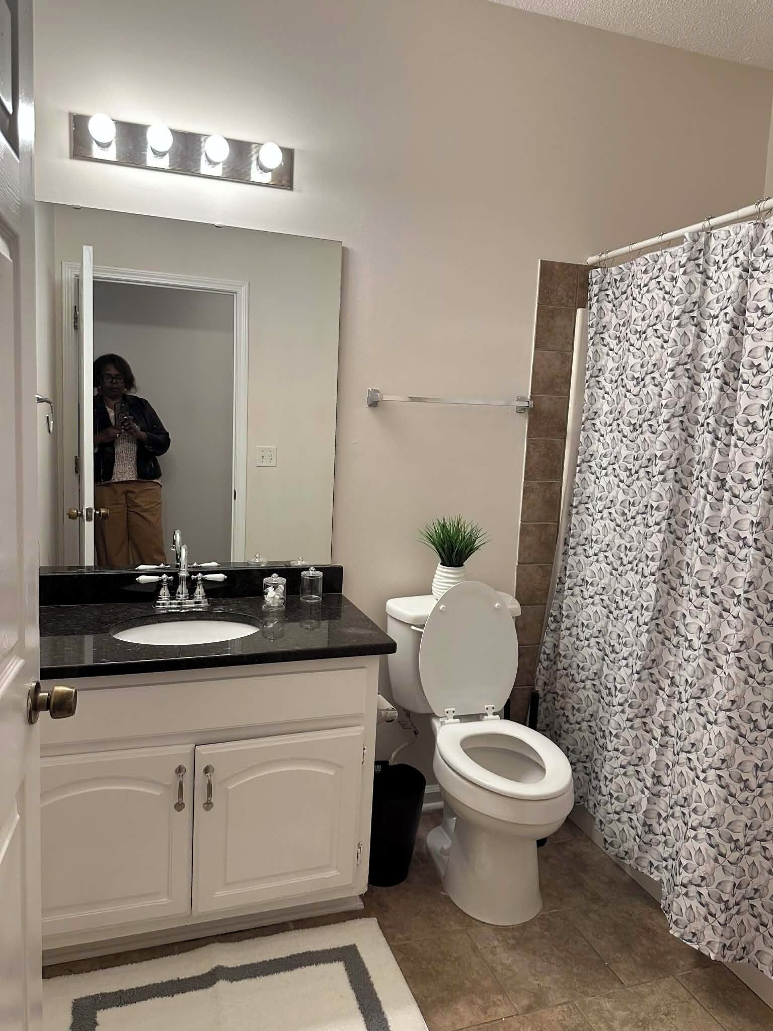 Et badeværelse med et toiletbord, vask, spejl og toilet.