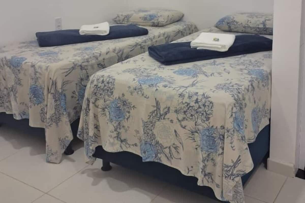 Una habitación con dos camas, cada una con ropa de cama floral y almohadas oscuras.