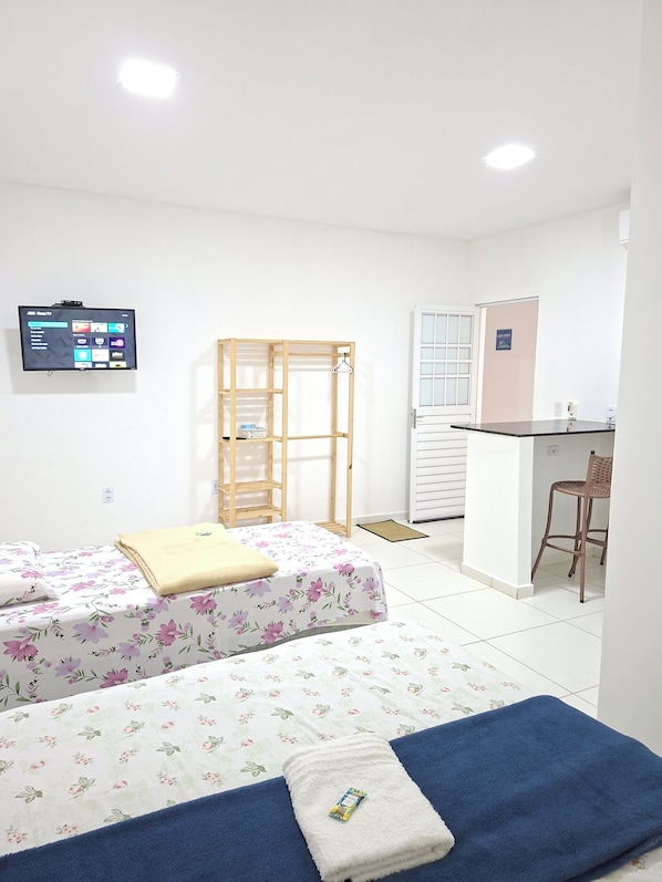 A room with two beds, a desk, a chair, a TV, and a wardrobe. - Pousada Beira Mar Suites (Maragogi)