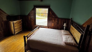 A bedroom with a wooden bed, a dresser, and a window with a view of trees. - New River Gorge National Park Sunsets, Rafting and Hiking trails. (Lansing)