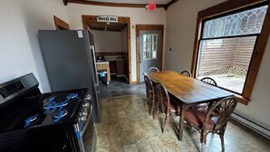 A kitchen with a wooden table and chairs, a refrigerator, a stove, and a window with a view of the outside. - New River Gorge National Park Sunsets, Rafting and Hiking trails. (Lansing)