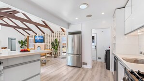 Una cocina moderna con una isla central, electrodomésticos de acero inoxidable y una estructura de techo de madera.