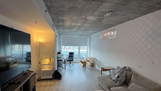 A modern living room with a large flat-screen TV, a sofa, a coffee table, and a dining area with chairs and a table. - Spacious Downtown 1 bedroom condo with Gym, Walk to Old Port (Montréal)
