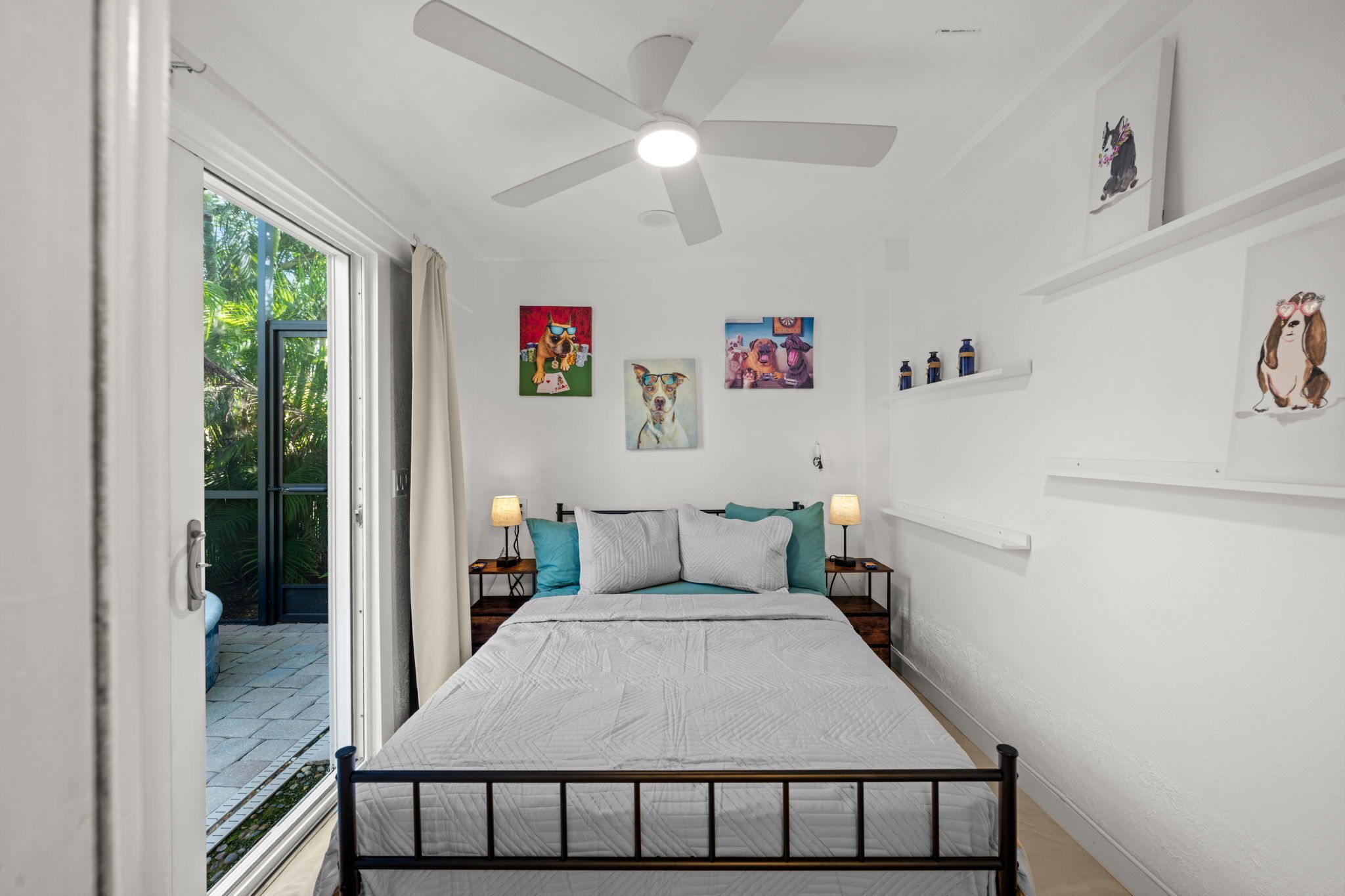 Ein Schlafzimmer mit einem Bett, einem Deckenventilator und Kunstwerken an den Wänden.