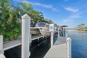 A dock with a boat, surrounded by palm trees and a clear sky. - Aurora Breeze Estate - The Heart of Matlacha Living (Matlacha)