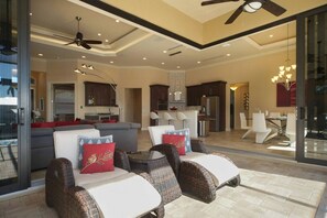 A spacious living area with a sofa, chairs, and a dining table. There is a kitchen in the background with modern appliances. - Sunshine Pearl Residence (Cape Coral)