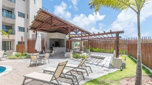 A patio with lounge chairs, a pool, and a pergola. - Flat 1Qt na Praia dos Carneiros-SH139 (Tamandaré)