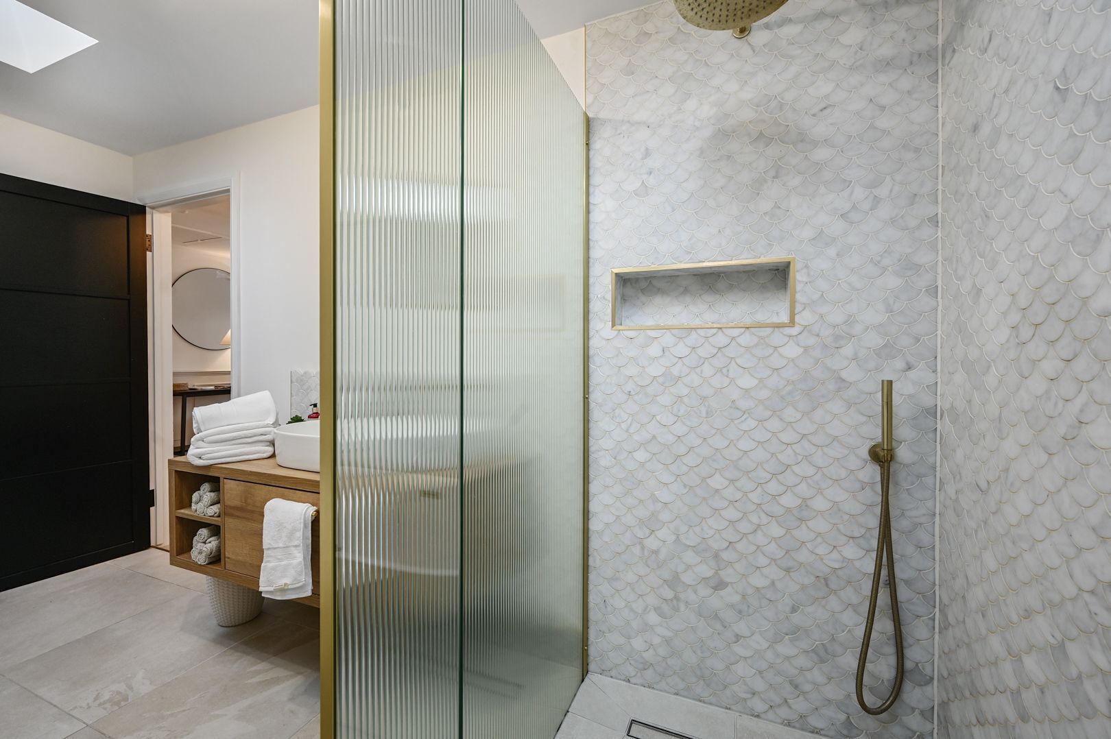 Une salle de bain moderne avec une douche à parois de verre, un mur en marbre et un lavabo intégré.