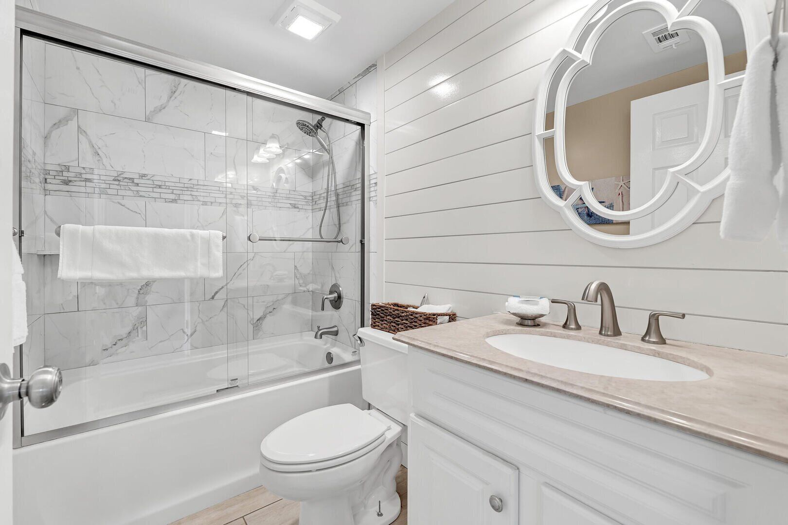 A modern bathroom with a glass-enclosed shower, a white toilet, a sink with a mirror, and a vanity with drawers.