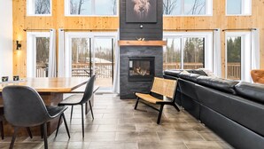 Een modern interieur met een open haard, houten wanden, een eetgedeelte en een zithoek.