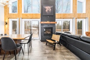 Ein modernes Interieur mit Kamin, Holzwänden, einem Essbereich und einer Sitzecke.