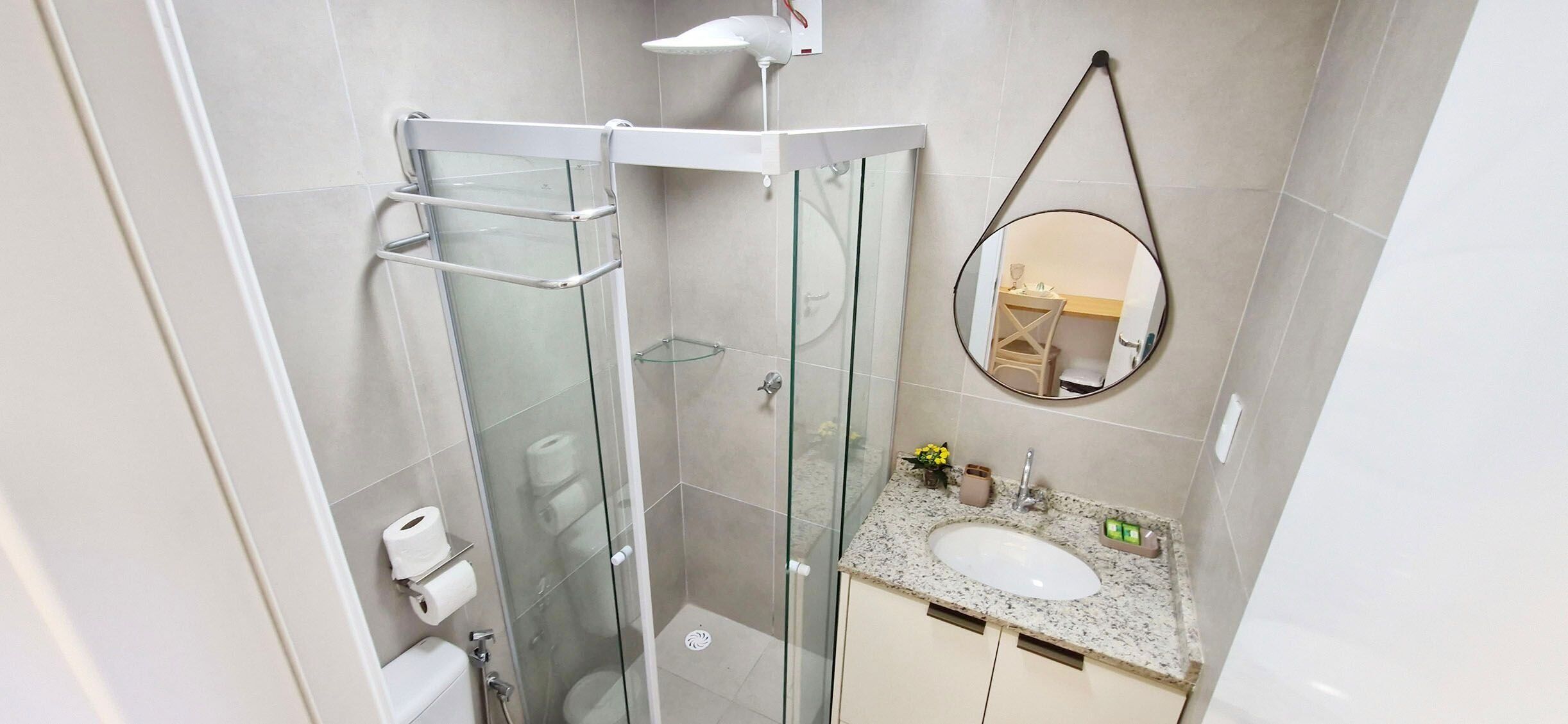 Une salle de bain moderne avec une douche à parois de verre, un lavabo avec un miroir et des toilettes.