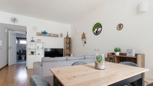 Una sala moderna con un sofá, una mesa de comedor de madera y un televisor.