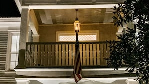 Un bâtiment à deux étages doté d’un balcon, d’une porte d’entrée ornée d’une guirlande et de deux lanternes fixées au mur.