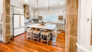 Une cuisine spacieuse avec des meubles blancs, un îlot central doté de sièges et un plancher en bois.