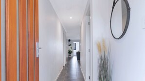 A hallway with wooden doors, a potted plant, and a mirror on the wall. - Dakabin Escape Modern Comfort near Dining and Shops (Dakabin)