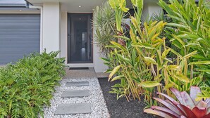 A modern house with a grey exterior, a black door, and a gravel pathway leading to the entrance. - Dakabin Escape Modern Comfort near Dining and Shops (Dakabin)