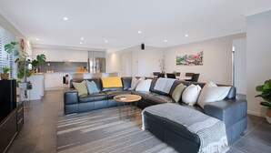 A modern living room with a sectional sofa, a coffee table, and a grey rug. - Dakabin Escape Modern Comfort near Dining and Shops (Dakabin)