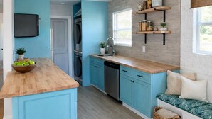 A kitchen with blue cabinets, wooden countertops, a built-in oven, and a window with blinds.