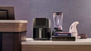 Una encimera de cocina con cafetera, licuadora, un libro titulado 'CHECKERS' y una botella de agua.