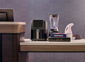 Una encimera de cocina con cafetera, licuadora, un libro titulado 'CHECKERS' y una botella de agua.