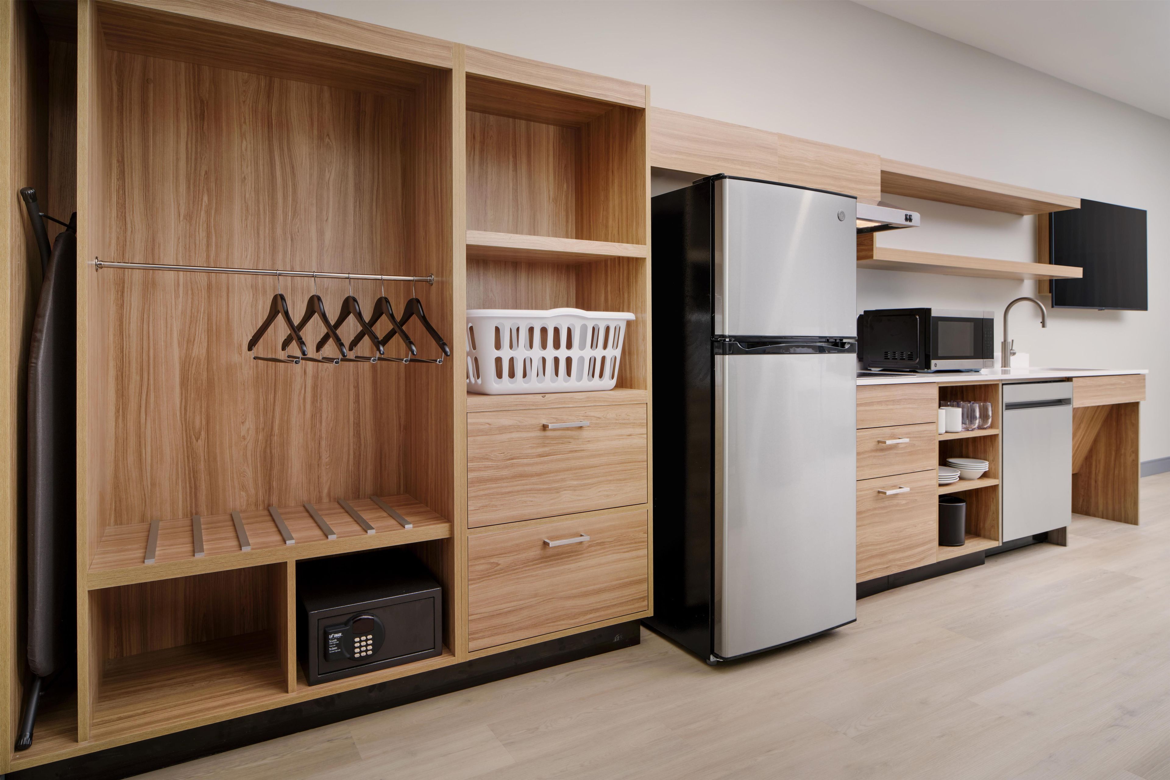 Una cocina moderna con refrigerador integrado, microondas y un armario de madera con una estantería colgante.