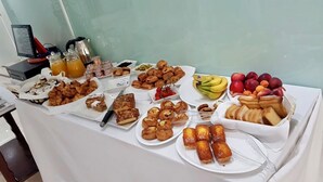 Una mesa de buffet con diversas opciones de comida, incluyendo pasteles, frutas y bebidas.