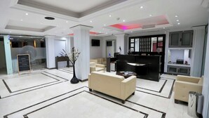 Un moderno vestíbulo de hotel con un mostrador de recepción, una zona de estar y un gran jarrón decorativo.