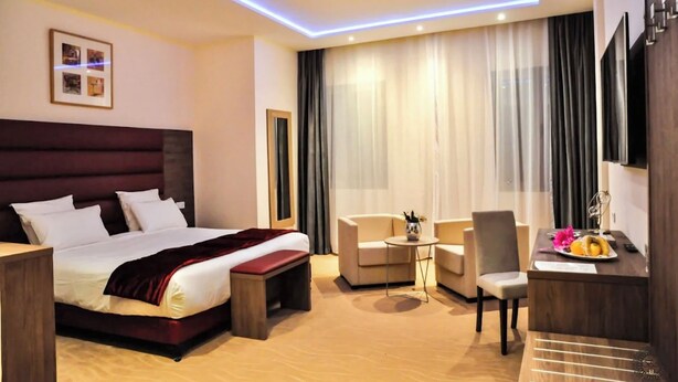 Una habitación de hotel moderna con una cama grande, un escritorio, una silla y un sofá.