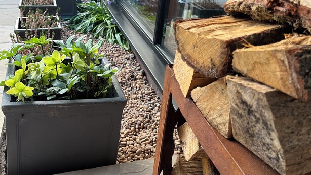 A garden with various potted plants and a stack of firewood. - Havendale (Chesterfield)