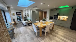 A modern kitchen with a dining area, a skylight, and a green-lit ceiling. - Havendale (Chesterfield)