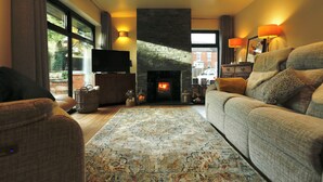 A cozy living room with a fireplace, a sofa, a television, and a large window. - Havendale (Chesterfield)