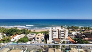 A coastal residential area with a prominent multi-story building, beachfront properties, and palm trees. - COPDS0110 - Pedra do Sal Privilege (Salvador)