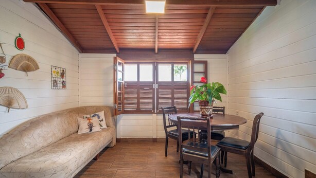 Une pièce chaleureuse avec un plafond en bois, un canapé, une table à manger avec des chaises et une plante en pot.