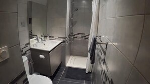 A modern bathroom with a toilet, sink, and shower. - Studio "A deux pas des thermes" in the heart of Uriage park. (Saint-Martin-d'Uriage)