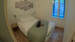 A bedroom with a bed, a window, and a world map artwork on the wall. - Studio "A deux pas des thermes" in the heart of Uriage park. (Saint-Martin-d'Uriage)