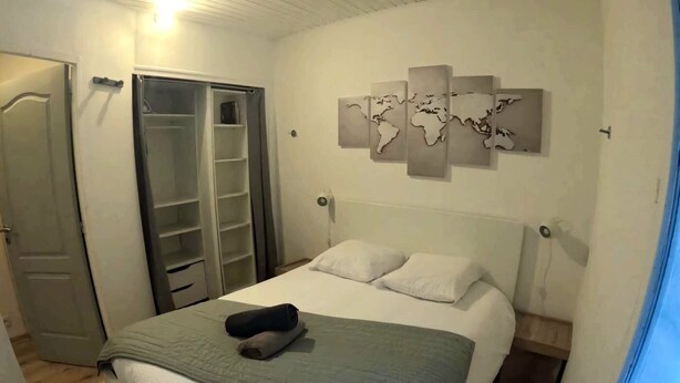 A bedroom with a bed, a wardrobe, a world map artwork, and a window. - Studio "A deux pas des thermes" in the heart of Uriage park. (Saint-Martin-d'Uriage)